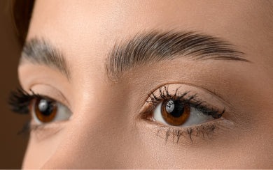 Close-up of a woman's laminated, brushed-up brown eyebrows.