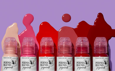 Six bottles of Perma Blend cosmetic pigments lined up against a purple background, each with matching fluid color splashes behind them ranging from light nude and pink to deep red and maroon.