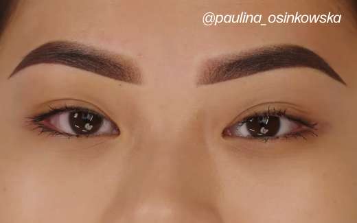 Close-up of a person's eyes showing a perfectly symmetrical pair of freshly done ombré powder permanent eyebrows.